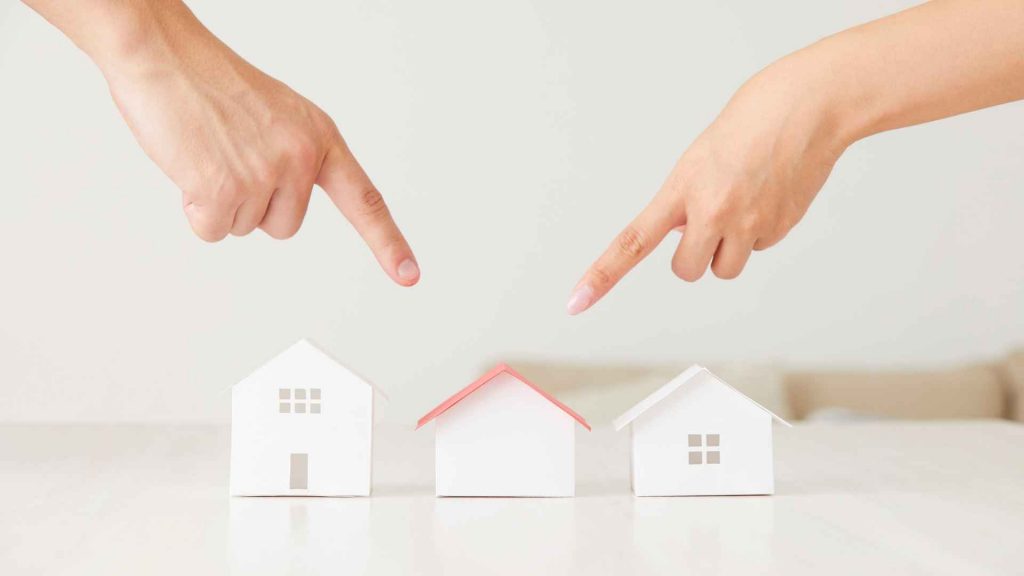Two hands pointing to different model houses, symbolising customer choice and decision-making as part of the Segmentation, Targeting and Positioning strategy.