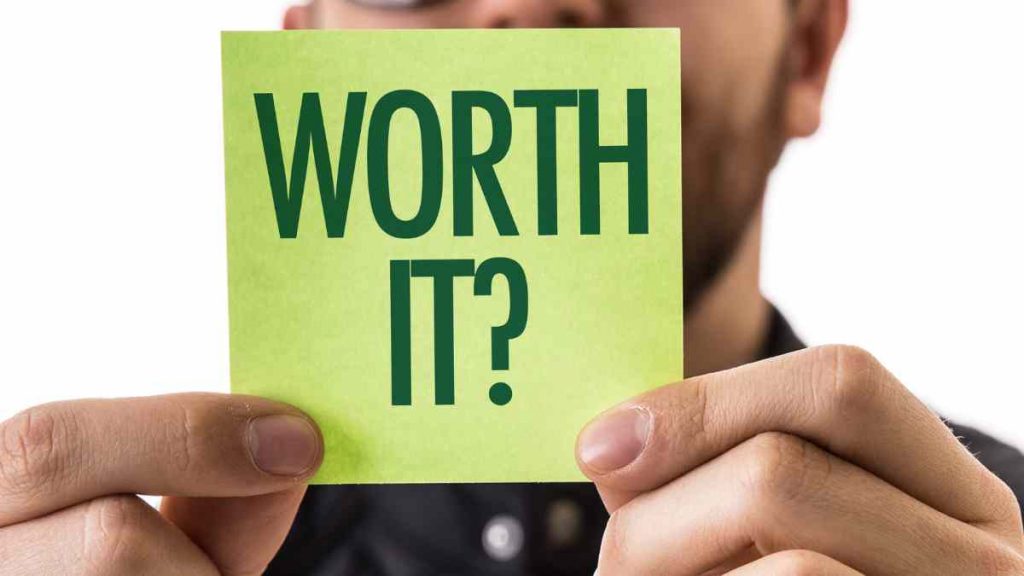 Business professional holding a green note that says “Worth It?” illustrating the value of hiring an email marketing agency.