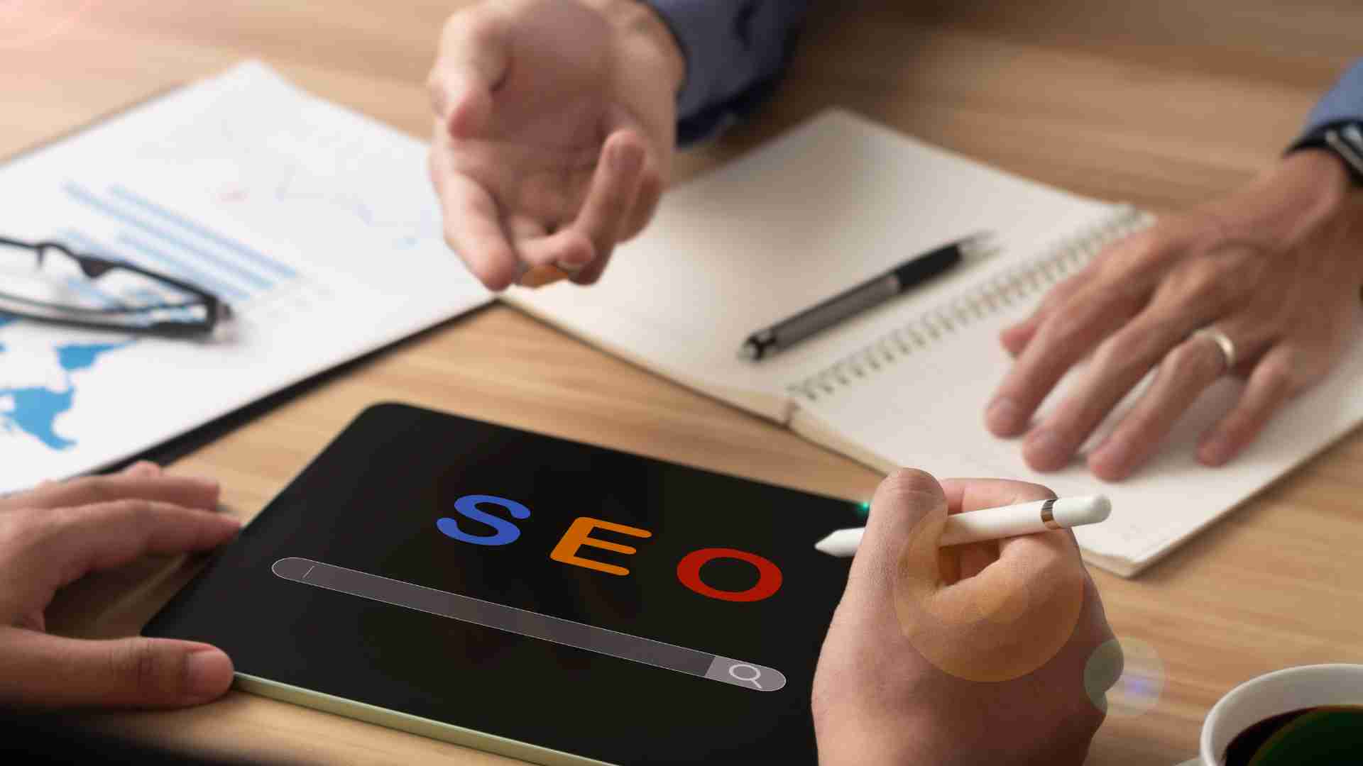 People working on a tablet displaying the word SEO, discussing strategies for SEO in digital marketing.