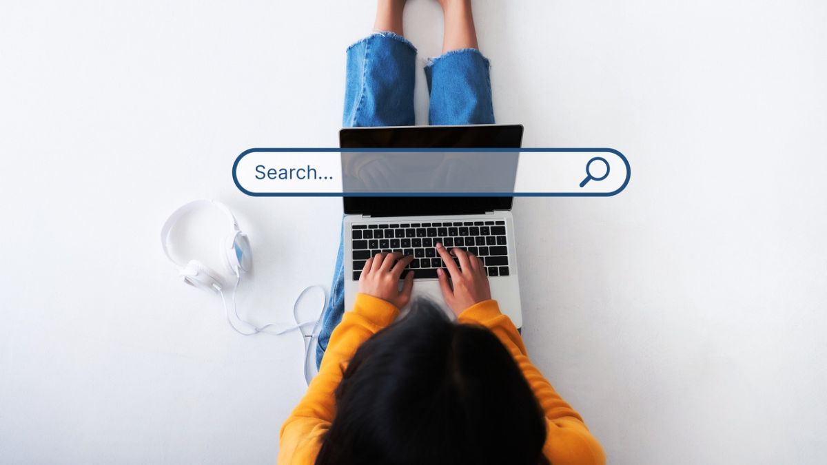 Person typing on a laptop with a search bar overlay, illustrating how do search engines work for everyday searches.