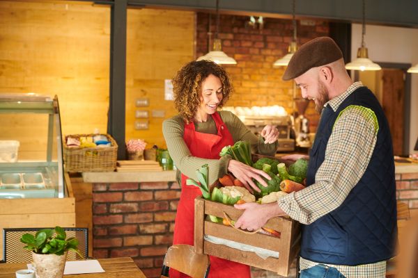 Two local business owners in a shop handling fresh produce, representing real-world relationships and community trust behind local SEO links.